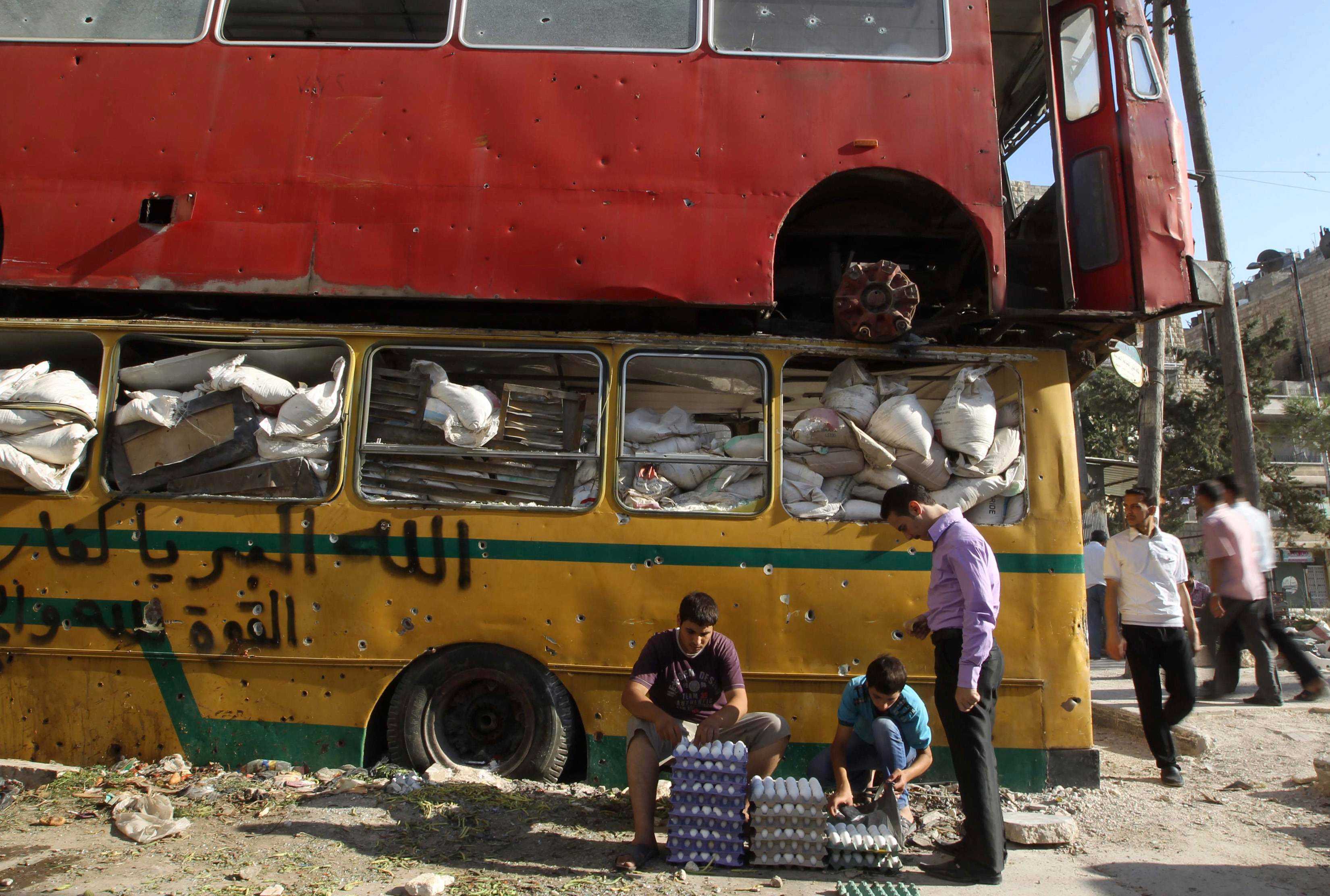 Men sell eggs in front of two buses filled with bags and cardboard.